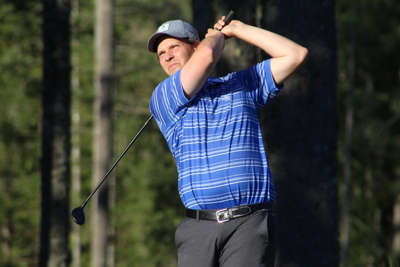 Man finishing his golf swing and looking up course