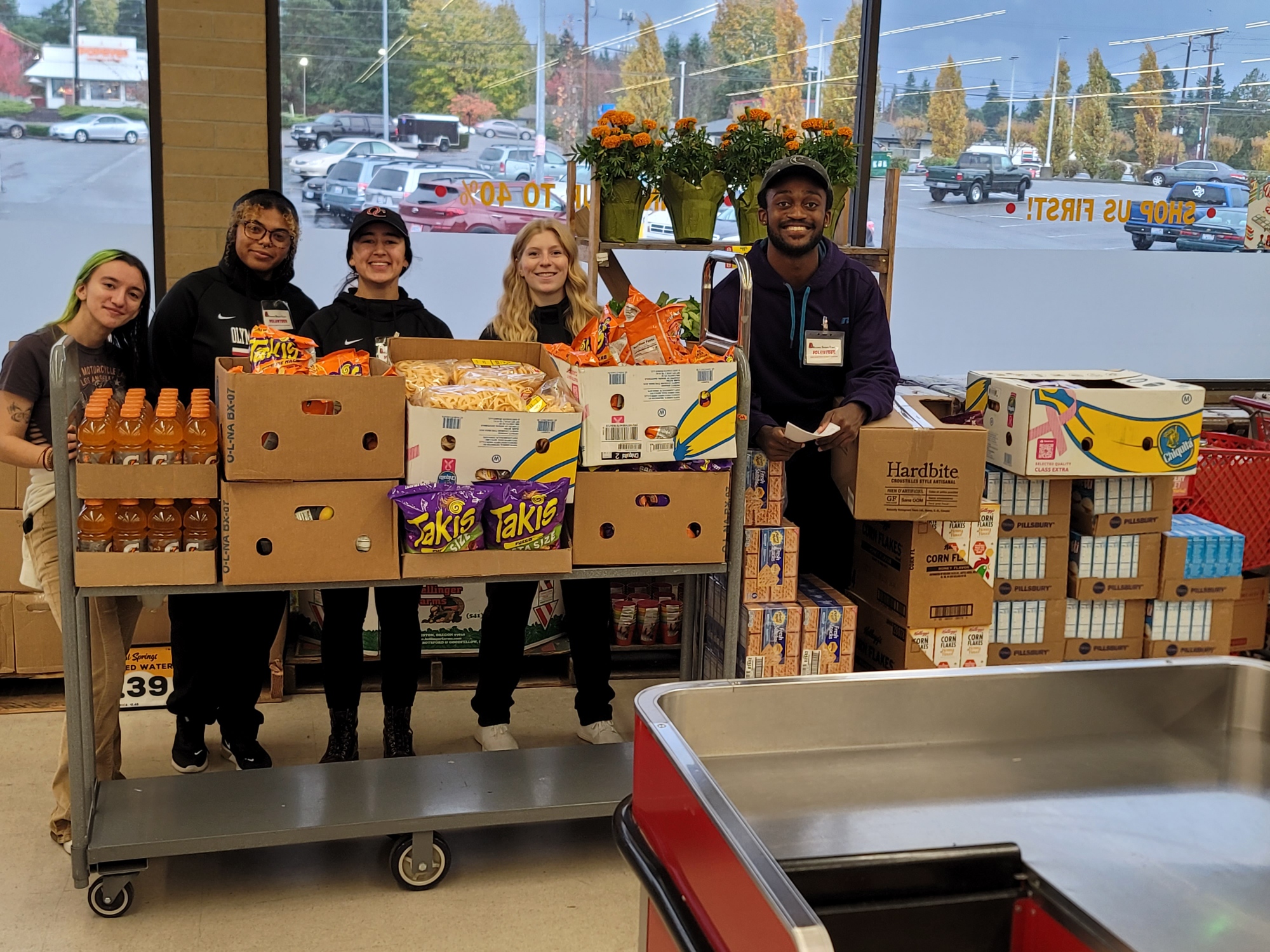 5 people pose behind a stack of donated food.